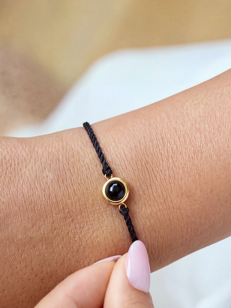 Wrist wearing a black cord Circle Photo Bracelet with a gold-rimmed photo gem