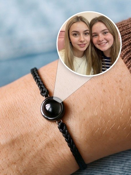 Black cord Circle Photo Bracelet on a wrist, with a close-up of the same photo of the sisters inside its gem