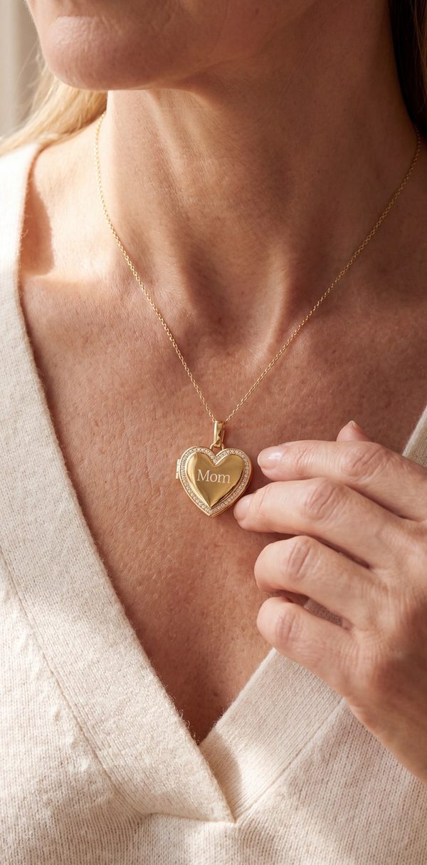 Woman in a cream sweater wearing an engraved gold heart locket necklace